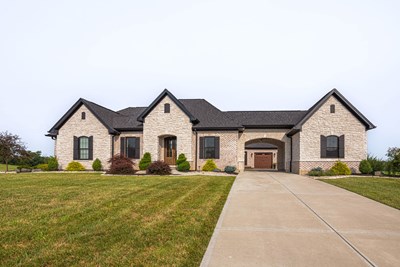 Glen-Gery | Limestone Cashmere building stone veneer on exterior of home with brick, black window shutters, and portico garage